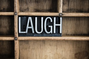 The word "LAUGH" written in vintage metal letterpress type in a wooden drawer with dividers.